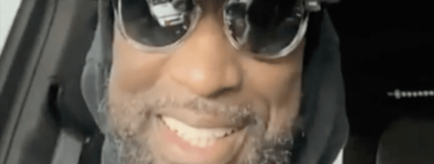 Smiling person wearing sunglasses in car.